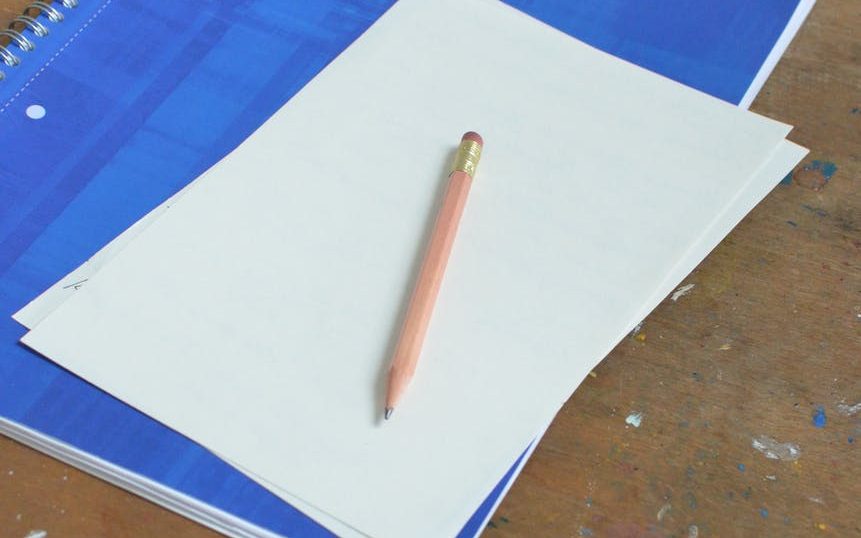 notebook and blank paper sheets with pencil on table